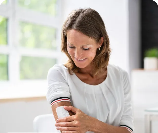 A woman applying a nicotine replacement patch to her arm