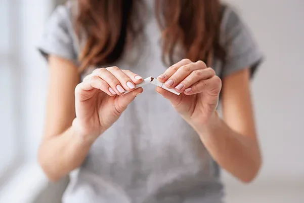 A woman breaking a cigarette in half